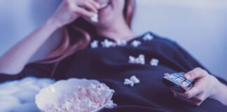 Woman on a couch eating popcorn