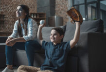 Young boy with a baseball and glove cheering on his favorite team while watching a Major League Baseball game with his mother.