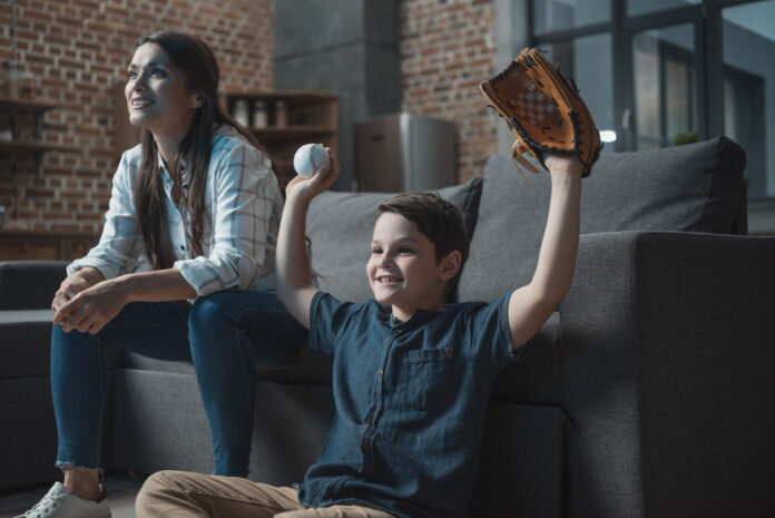 Young boy with a baseball and glove cheering on his favorite team while watching a Major League Baseball game with his mother.