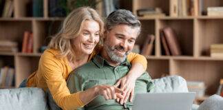 Middle aged couple smiling while safely browsing the Internet on a laptop
