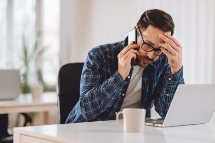 Man on the phone worried after visiting an illegal streaming website on his computer