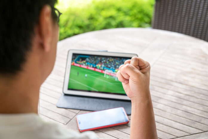 Man streaming a soccer match on his tablet while at home