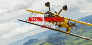 A yellow plane doing a barrel roll over mountains