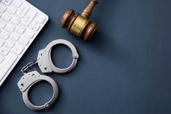 A computer keyboard with handcuffs and a judge’s gavel.