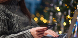 How to Spot Holiday Fraud and Shop Safely This Season Female hands on the laptop with credit card and blurred bokeh lights