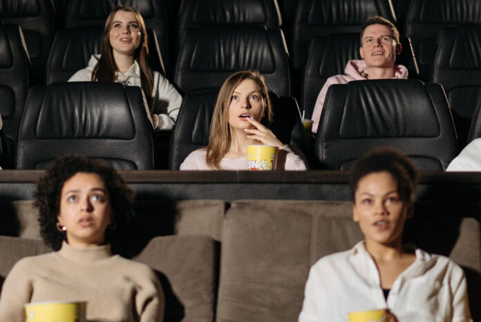 Moviegoers watching a film in a theater, representing popular and top-rated movies.