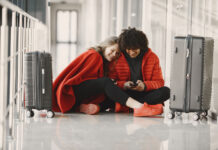 Is an Unsecured Public Wi-Fi Network Safe for Streaming? Two happy people in red waiting in airport with luggage sharing wifi on mobile device